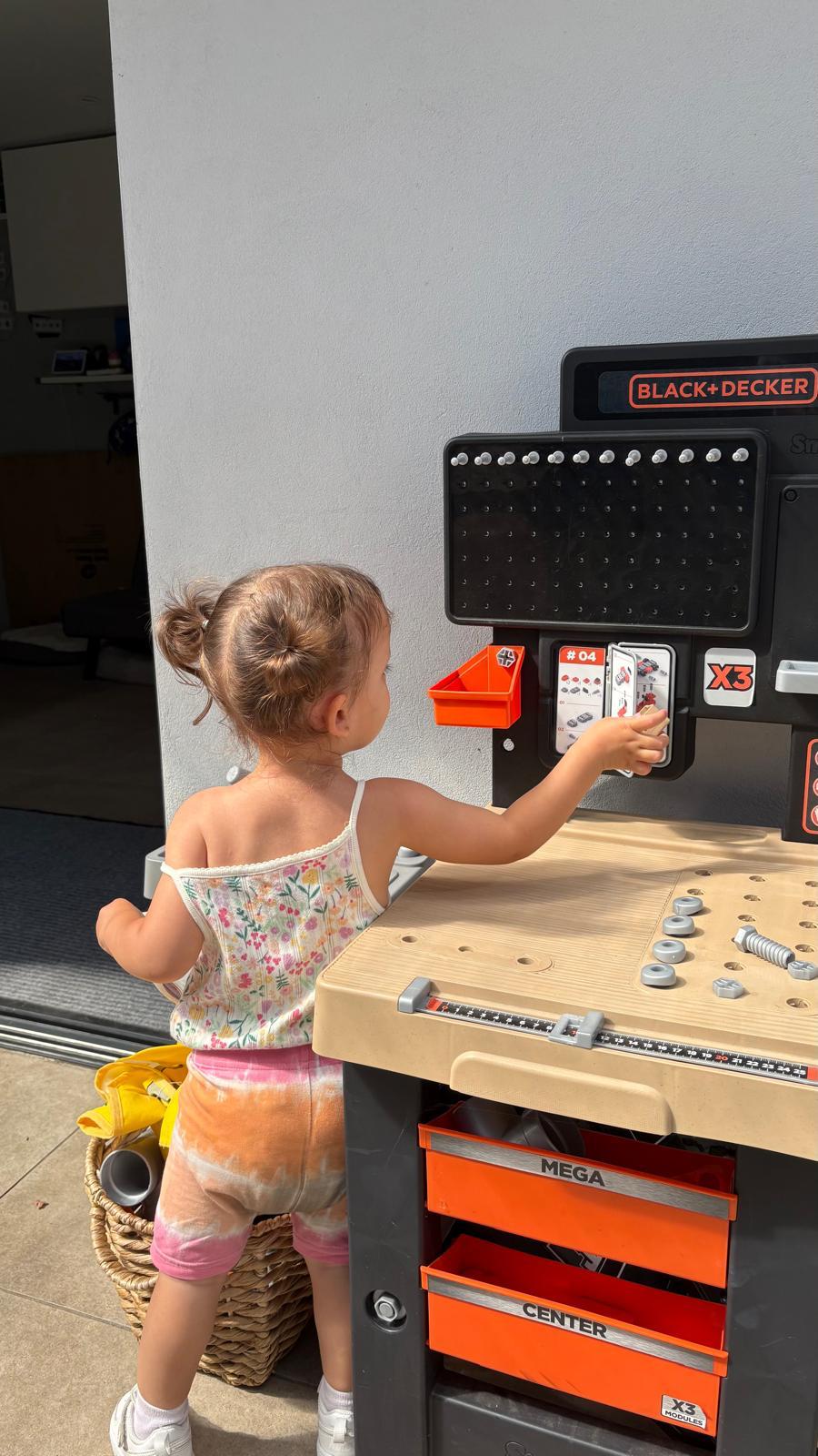 A toddler playing with a toy workbench set